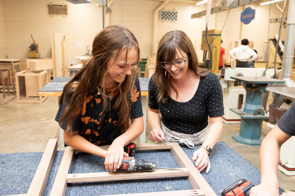 student and teacher creating a wooden frame
